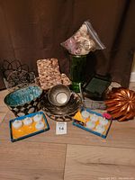 Wide view of lot showing all baskets, containers, floating tea lights, decorative wood slices in green glass vase, and copper bundt pan.