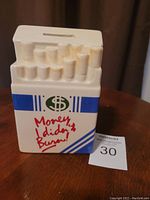 Front view of ceramic coin bank with cigarette shape top, text and slot