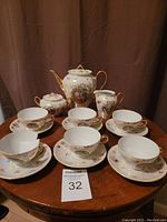 Full set of demitasse cups, saucers, teapot, sugar bowl, and creamer displayed on table