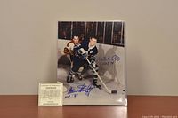 8x10 black and white hockey action photo featuring Montreal Canadiens' Henri Richard and Toronto Maple Leafs' Allan Stanley, both players' signatures and Hall of Fame years in blue ink visible on the photo, with accompanying certificate of authenticity.