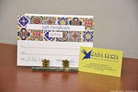 Photo of the $25 gift certificate and a business card for Casa Lucia, showing the gift certificate design, value, and handwritten date.