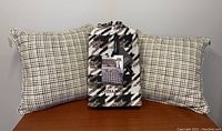 Two throw pillows with small check pattern and packaged Riviera Maison cotton flannel duvet cover with large houndstooth pattern.
