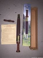 17th Century Highland Dirk replica with wood handle, brass fittings, leather sheath and strap, original box, and information leaflet.