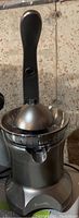 Side view of Breville Citrus Press Juicer showing metal lever handle, metal base, strainer bowl and spout.