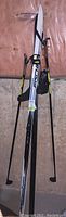 Fischer cross country skis with bindings and poles shown vertically on floor with pink insulation background.