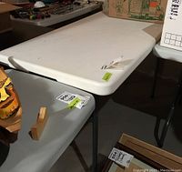 White folding resin table top with rounded edges in storage setting.