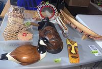 Overview photo showing entire lot items including goose decoy, wood masks, canoe, dream catcher, and woven basket.