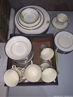 Table showing stacks of plates and box of cups and saucers