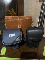 Two binocular cases, one marked Jennoptik IW and one vintage leather Moreau Paris case.