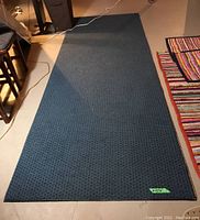 Full view of large blue textured rug with measuring tape showing 10ft 3 1/4 inches size