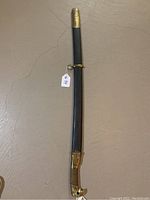 Fully sheathed sabre showing black leather scabbard and brass fittings