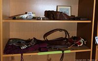 Shelf displaying WWI bandolero, leather pouch, Sam Browne belt with strap, two leather-wrapped swagger sticks, cummerbund and Union Jack flag