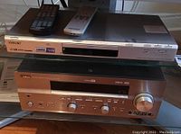 Yamaha RX-V757 AV receiver and Sony DVD player stacked with their remote controls on top.