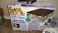 Photo of the boxed Pure Comfort queen size raised air bed featuring zebra print sides and a dark brown top surface, branding and usage details visible on box.