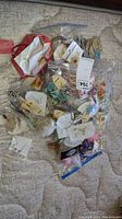Image showing a pile of over forty pieces of costume jewelry earrings in individual bags and packaging on a fabric surface.