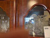 Full view of all glass items on china cabinet shelf, showing decanters, candy dishes, and vase together