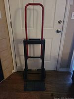 Photo of the hand truck dolly showing its red handle, black metal frame, and wheels.