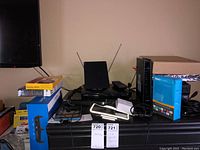 Lot overview with Linksys router box, Apple iPhone, Roku box, cables on black dresser surface