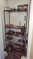 Full view of shelving unit holding multiple silverplate items including platters, bowls, candelabra, and trays.