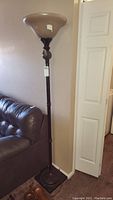 Full view of the 72 inch tall floor lamp showing the entire lamp from base to top shade, placed beside a sofa and wall.