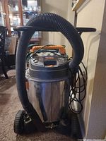 Front view of Ridgid Professional industrial vacuum with flexible hose attached and black handle-bar on top.