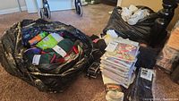Wide view of all items in black bags on floor near furniture, showing mix of packaged leggings and loose socks.