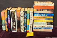 Photo showing a row of 21 fiction books in hardcover and paperback formats. Titles include various popular contemporary authors.