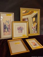 Full view of the lot showing the gold framed mirror, five framed prints including the 'Union Walk' tall watercolor street scene, floral prints, and one empty gold frame placed on a dark cloth surface.