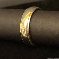 Close-up view of men's white gold wedding band showing polished surface and millgrained edges.