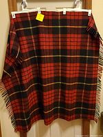 Red and black plaid wool throw hanging, showing full size and pattern.