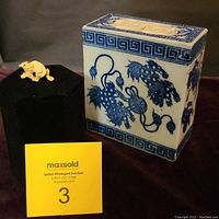 Photo showing both the blue and white ceramic opium pillow and the small carved dragon button on display, with a MaxSold auction marker.