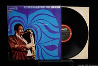 Vinyl LP partially removed from generic white inner sleeve, showing black vinyl and record label with orange-red and black design marking AS-9161 on Impulse! label.