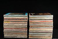 Two stacks of classical vinyl record LPs photographed side by side on a black background to show the thickness and quantity.