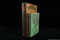 Three vintage outdoors books standing upright showing covers and spines under soft lighting on black background.