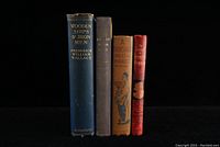 Front view of four vintage hardcover books partially visible titles and colors against black background