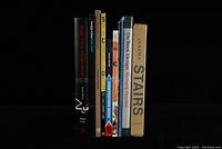 Front view of all 10 design books standing upright, showing spines and titles including Meggs' History of Graphic Design, Poster Girls, Soviet Commercial Design, How Posters Work, On Book Design, Jansma Stairs.