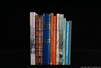 Front view of the 11 local history books standing together showing a range of colors, titles and bindings.