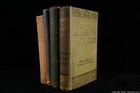 Four antique cook books grouped showing various covers and spines, including Mrs Beeton's All About Cookery