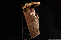 Full view of the Native doll seated in the leather cradleboard with wooden frame and beadwork.