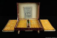 Open Mahjong box showing tiles displayed in three trays and instruction booklet inside lid