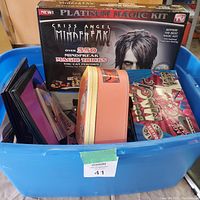 Blue plastic storage bin filled with multiple boxed magic sets including Criss Angel Mindfreak Platinum Magic Kit and a colorful vintage magic set box.