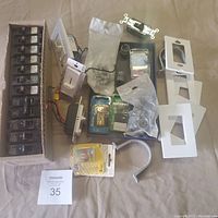 Overview photo showing all electrical components including Siemens breakers, dimmer switches, faceplates, fuses, and hardware spread on table