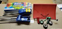 Overview photo showing unopened pack of Bunch O Balloons water balloons, two blue Wolverine claws toys, and Fly Wheels rippers with launching ramp.