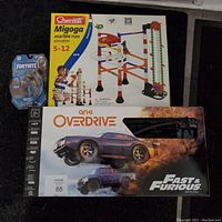 Overview photo showing the Fortnite figurine, Migoga marble run box, and Anki Overdrive race car track box.