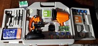 Full view of travel case with microscope and accessories including sample containers, magnifying glass, and other small tools