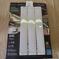 Front view of three identical ultra-thin LED under cabinet light panels on product box with branding and info.