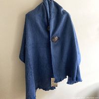 Full view of the blue alpaca shawl hanging showing size and wooden toggles.