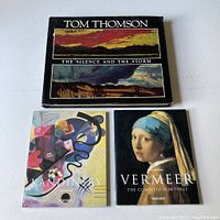 Front cover of Tom Thomson hardcover book with two landscape paintings and titles visible. Front covers of Taschen paperback books Kandinsky and Vermeer showing colorful abstract and portrait artwork.