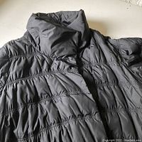 Close-up of coat showing quilted horizontal seams and high collar