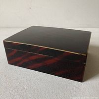 Vintage 1970's faux tortoise lacquerware box angled view showing gold trim edge and glossy finish.